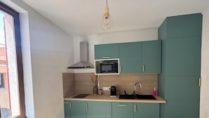 A compact kitchen with teal cabinets, a microwave, and a coffee maker. - Historic center apartment  (Narbonne)