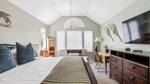 Un dormitorio con cama, cómoda, escritorio y televisor.