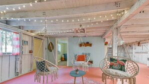 A room with two hanging chairs, a small table, and a patterned rug.