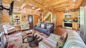 Ein Blockhaus-Interieur mit Wohnzimmer, Küche und Treppe.