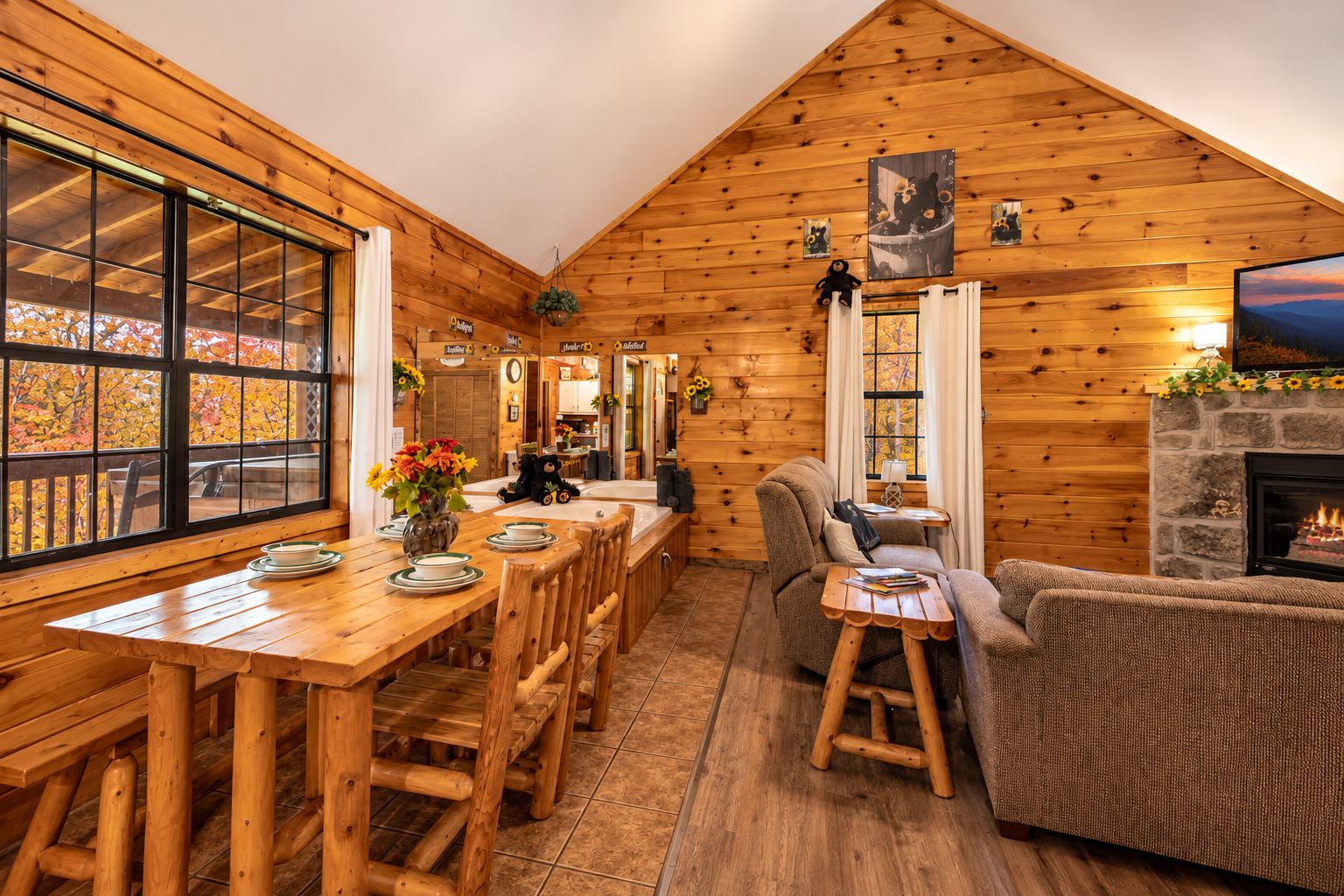 A cozy cabin interior with a wooden dining area, a fireplace, and a television.