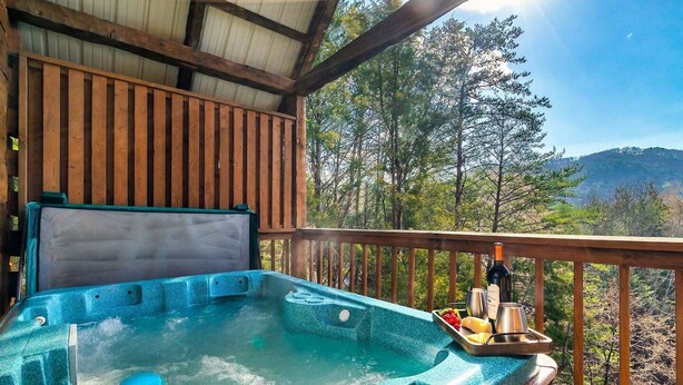 Un jacuzzi con terraza de madera y una vista panorámica de árboles y montañas.