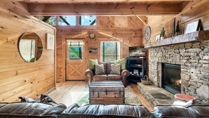 Un acogedor interior de cabaña con chimenea de piedra, sofás de cuero y techo de madera.
