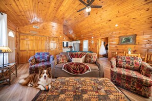 A cozy cabin interior with wooden walls, a ceiling fan, and a dog resting on a rug. - Hot Tub with Mountain Views, Fire Pit & Pool Table (Sevierville)