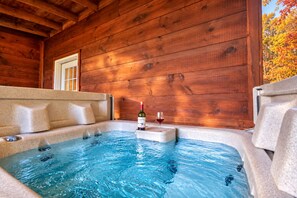 A hot tub with a bottle of wine and a glass, wooden walls, and a window. - Hot Tub with Mountain Views, Fire Pit & Pool Table (Sevierville)