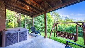 Un patio coperto con idromassaggio, altalena e panchina.