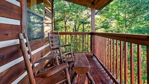 Une cabane en bois avec une véranda, un banc et une chaise.