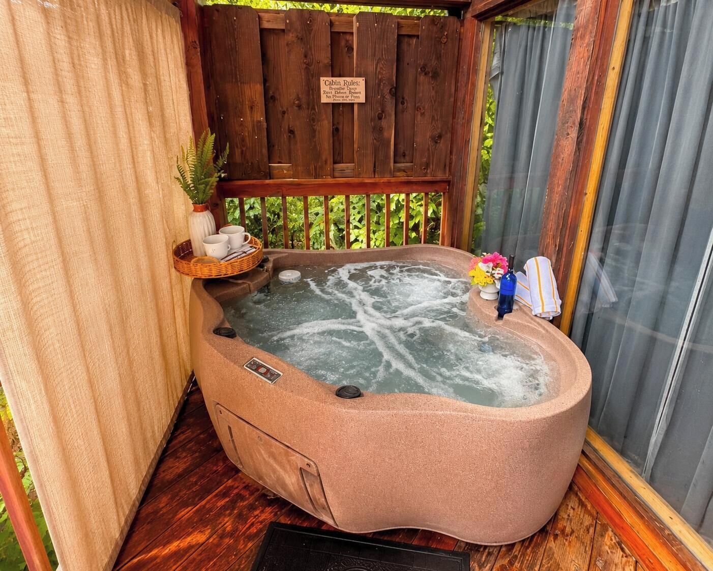 A hot tub with a wooden deck, a sign with cabin rules, and a small plant.