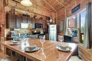 A wooden cabin kitchen with a central island, wooden cabinets, a refrigerator, and a coffee maker.