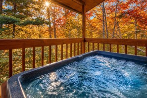 A hot tub with a wooden deck and a view of autumn trees. - Hot Tub, Fire Pit & Mountain Views Near Dollywood (Sevierville)