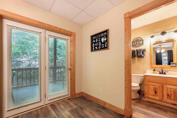 Un baño con muebles de madera, inodoro y ventana con persianas.