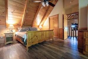 A wooden bedroom with a bed, nightstands, and a closet.