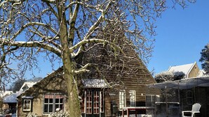 Un bâtiment en bois doté de grandes fenêtres et dont le sol est recouvert de neige.