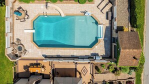 Ett flygbildsfoto av en bostadsfastighet med en swimmingpool, utemöbler och en trädgård.