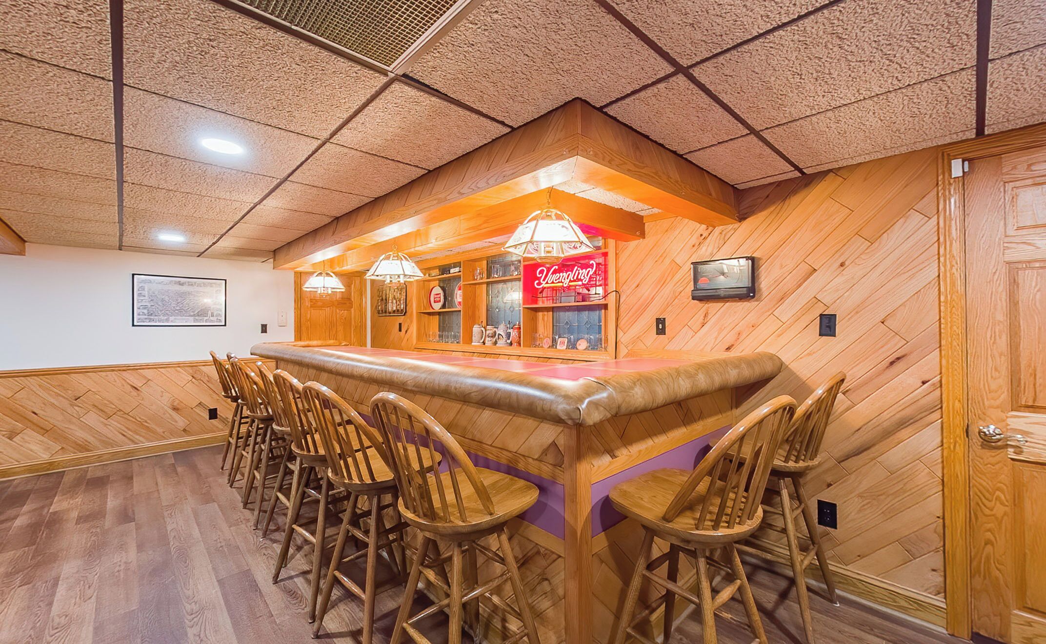 Un espace bar avec des tabourets et un comptoir en bois, agrémenté d’une enseigne « Vermilion ».