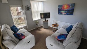 A living room with two grey sofas, a TV, a radiator, and a painting on the wall. - Spacious Apartment with Private Terrace (Newtownards)