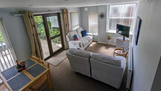 A spacious living area with a sofa, a television, and a dining table with chairs. - Spacious Apartment with Private Terrace (Newtownards)