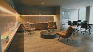 Un espacio de oficina moderno con un mostrador de recepción de madera, sillas de cuero y una mesa redonda.