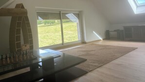 Un dormitorio en el ático con un tragaluz, un tablero de ajedrez y un amplio ventanal corredera que da a un jardín césped.