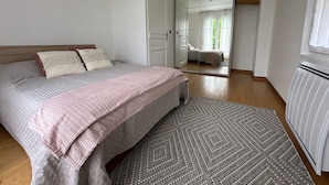 Un dormitorio con cama, un espejo grande, un radiador y vistas a otra habitación.