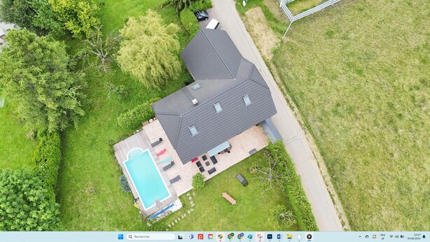 Vista aérea de una casa con piscina, patio y jardín cercado.