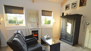 A living room with a fireplace, a sofa set, a coffee table, and a cabinet. - Holiday Home in Eerbeek near Veluwe (Eerbeek)