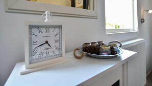 A wall-mounted clock with Roman numerals and a 'LONDON' label, a mirror reflecting a room, and a shelf with jars and a pine cone. - Holiday Home in Eerbeek near Veluwe (Eerbeek)