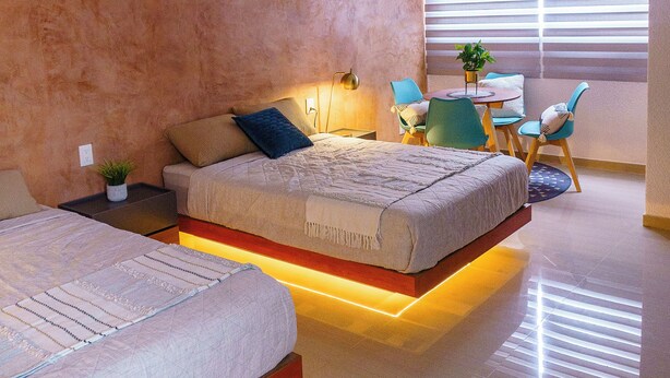 Un dormitorio moderno con dos camas, una mesita y sillas.