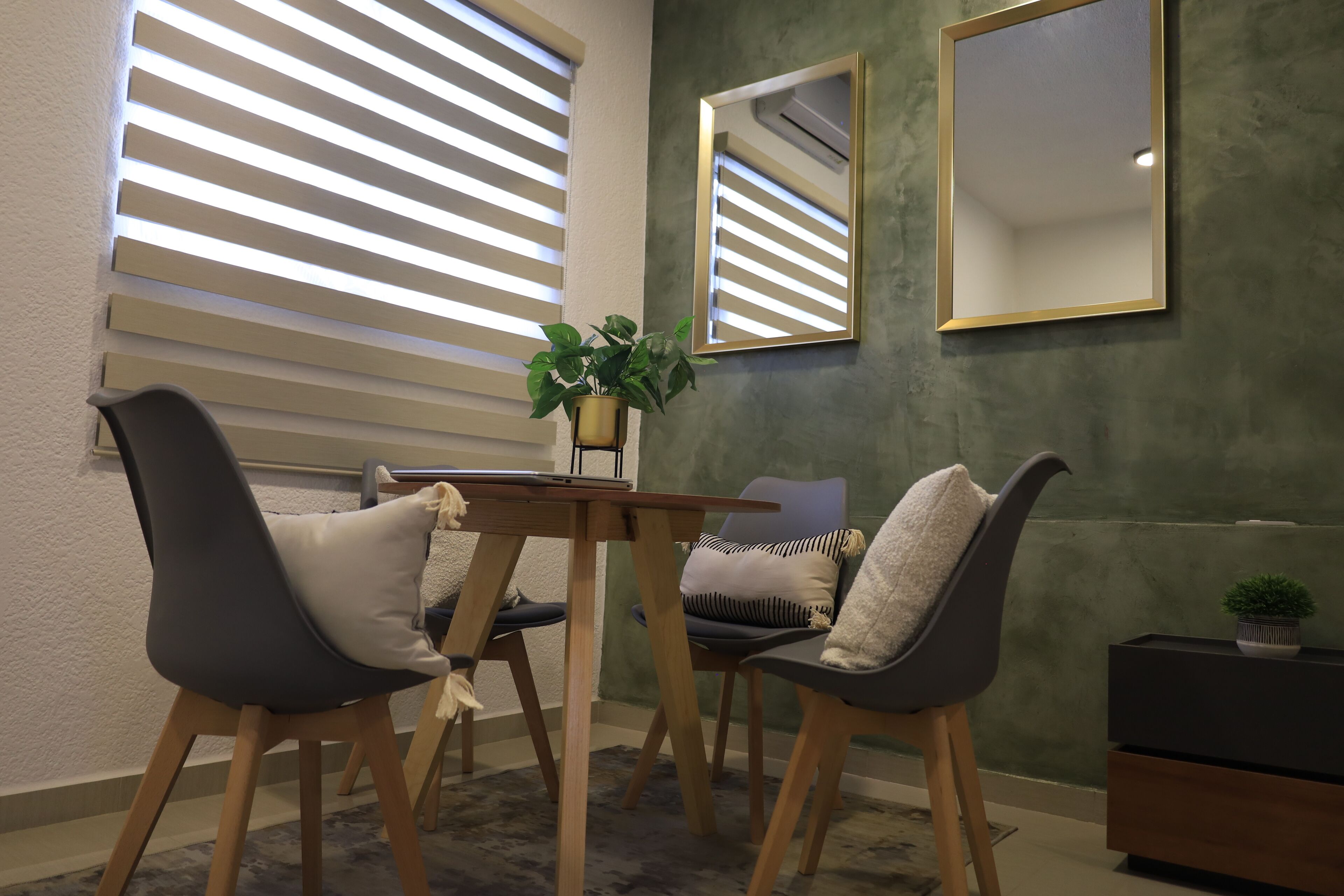 Un comedor con una mesa, sillas y una planta en maceta.