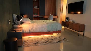 Un dormitorio moderno con cama, mesita de noche, lámpara, televisor y escritorio de madera.