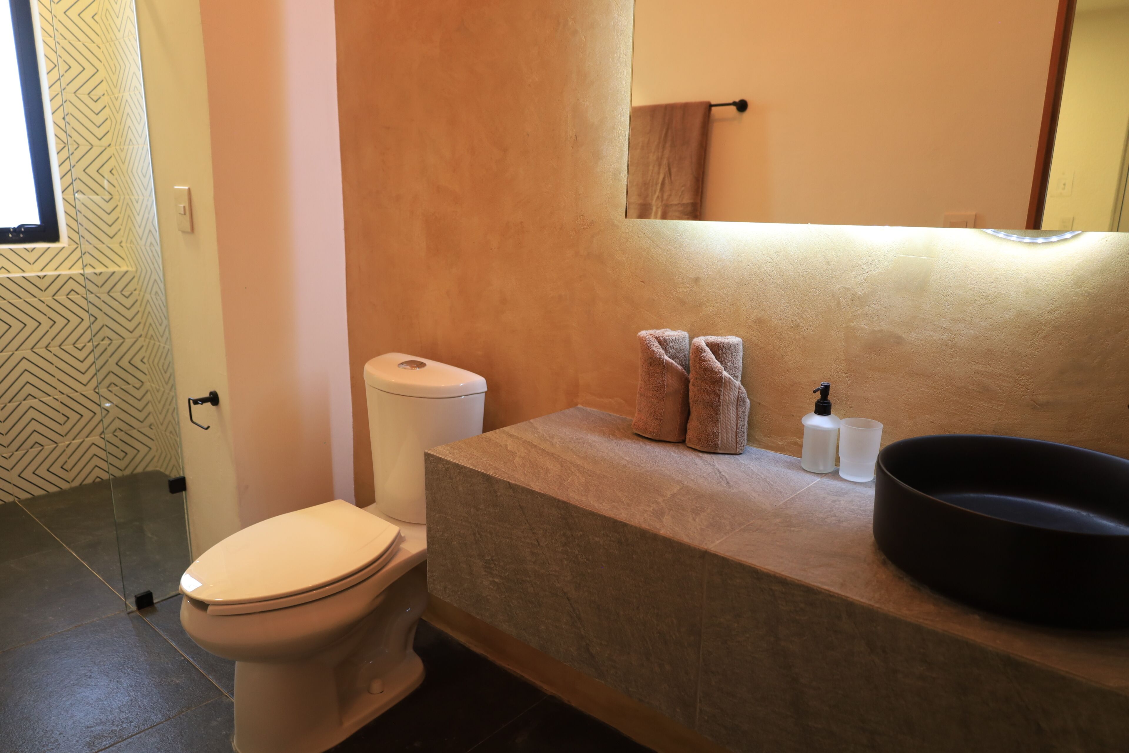 Ein Badezimmer mit Toilette, einem Waschbecken mit großer Schüssel und einem Spiegel darüber.