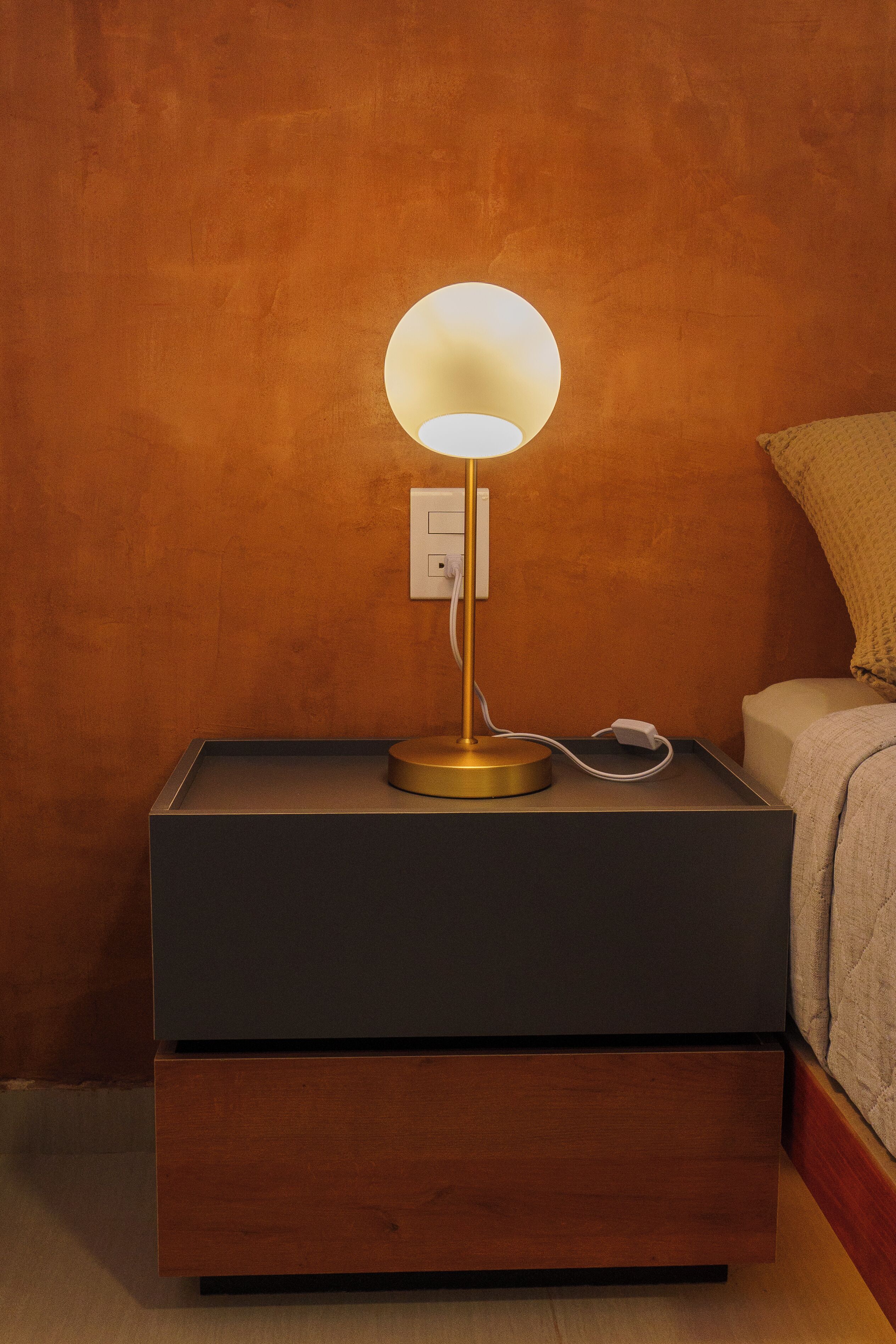 Ein Nachttisch mit Lampe, Steckdose und Schublade.