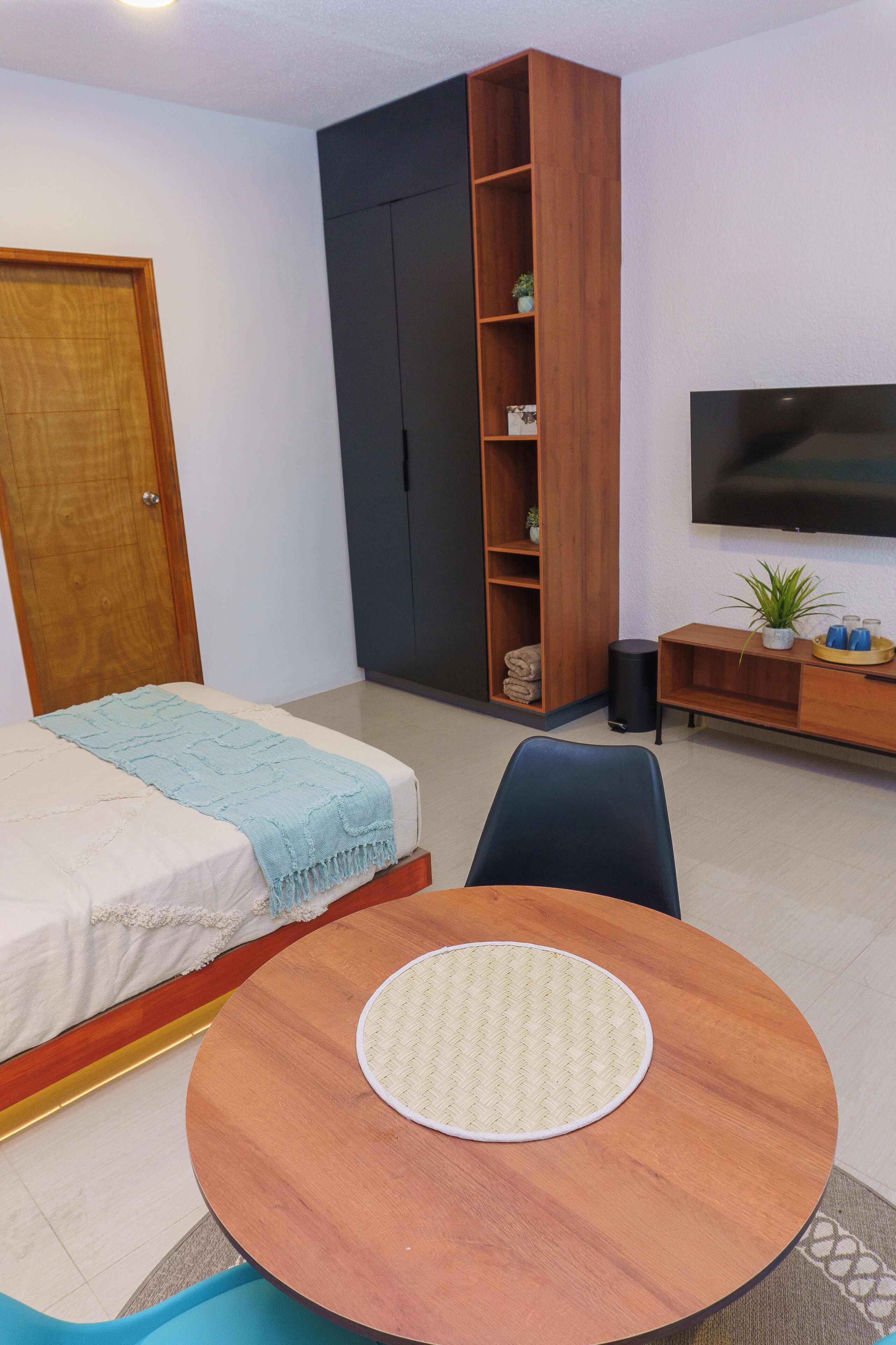 Un dormitorio con una cama, un armario de madera, un televisor y una mesita con un tapete.