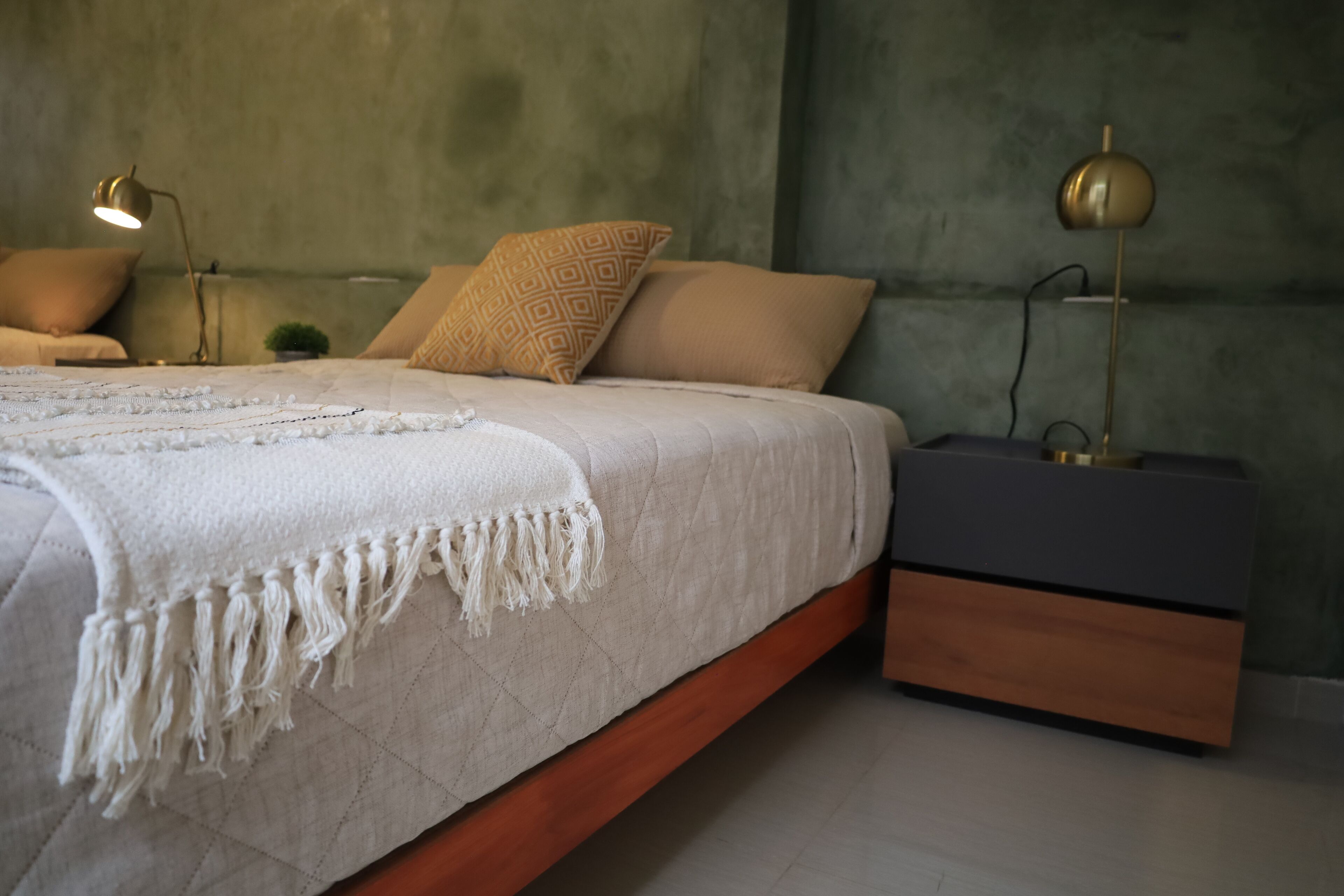 Quarto com cama, mesas de cabeceira e apoio para objetos pessoais.