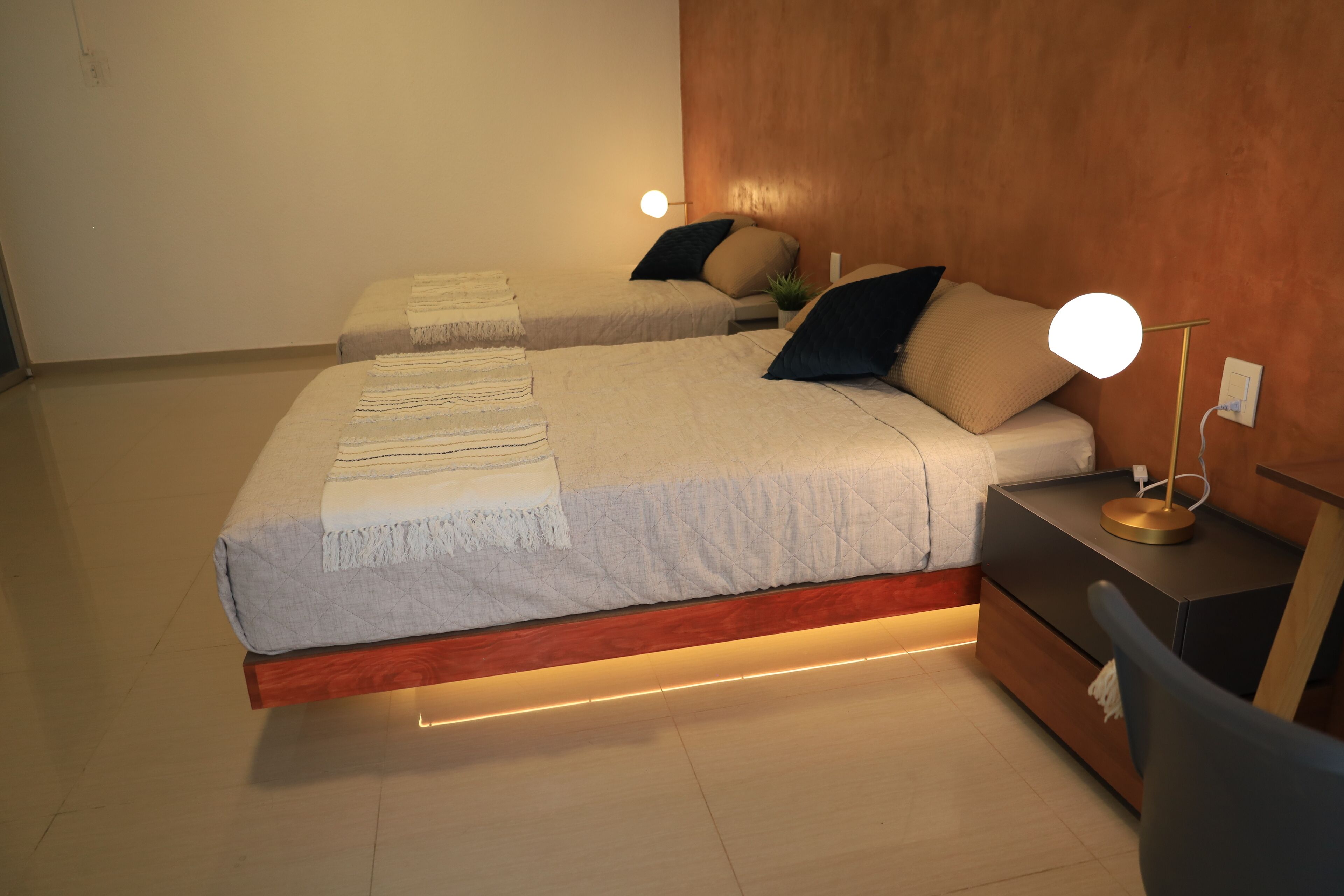Ein modernes Schlafzimmer mit zwei Betten, Nachttischlampen und einem Nachttisch.