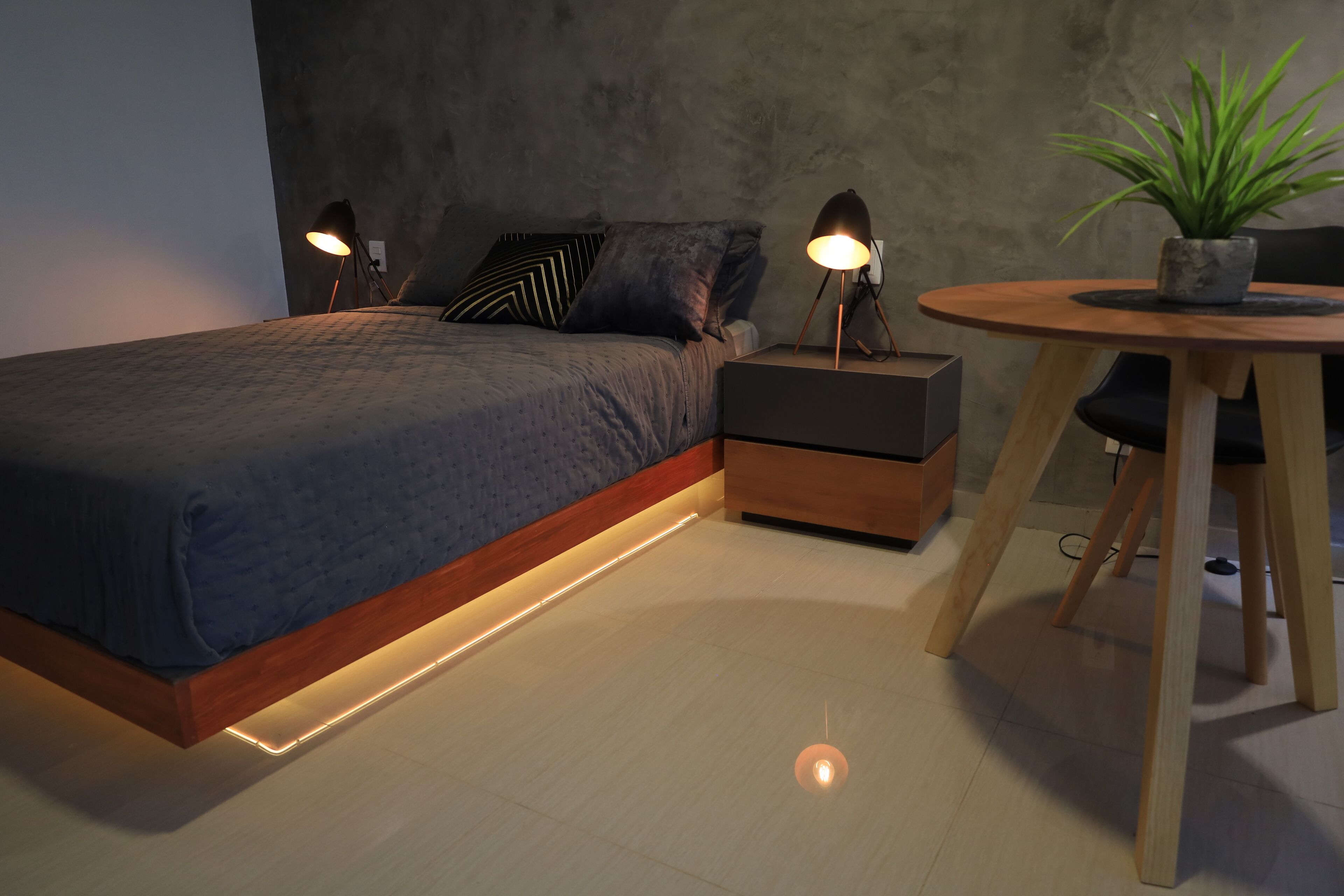 Une chambre à coucher moderne avec un lit, des lampes de chevet, une petite table avec une plante et une table de nuit.