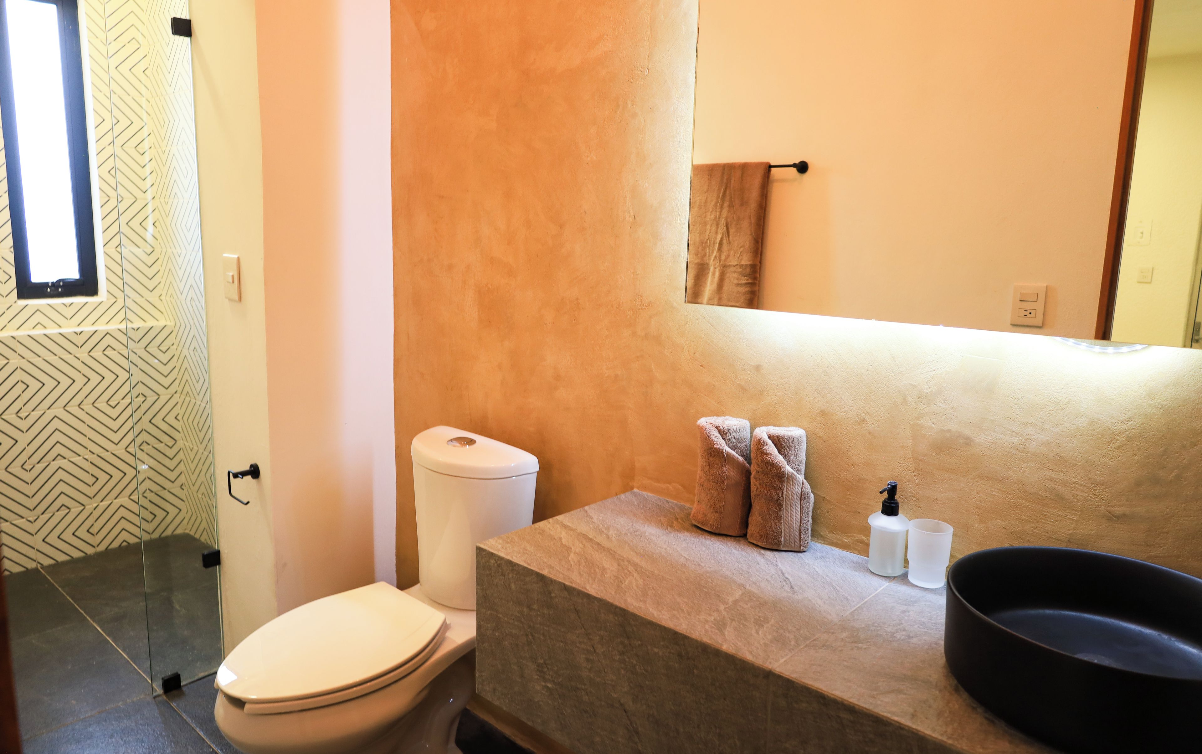 A bathroom with a toilet, a sink, and a mirror.