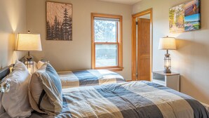 A bedroom with two beds, a window, and a door. - Cozy Corner - East end home (Ely)