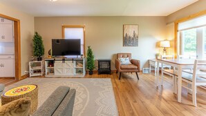 A living room with a TV, sofa, and dining table. - Cozy Corner - East end home (Ely)