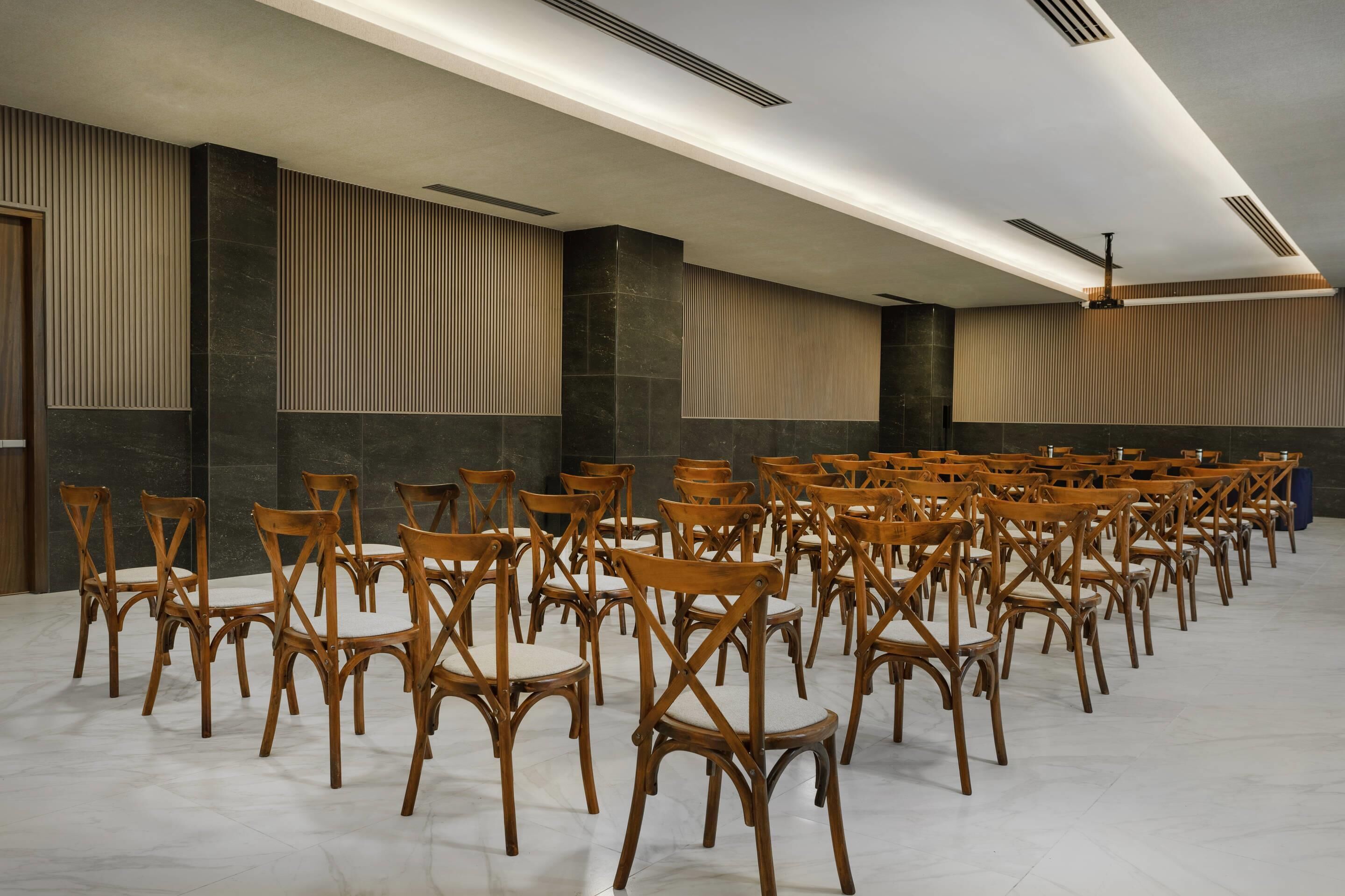 A room with rows of wooden chairs, a ceiling fan, and vertical wooden slats on the walls.