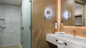A modern bathroom with a glass shower enclosure, a vanity with a large mirror, and a towel rack.