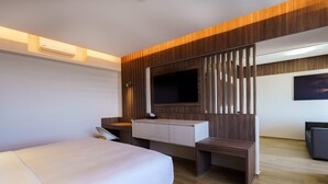 A modern hotel room with a large bed, a desk, a TV, and a seating area. - Radisson Puebla Angelopolis (Puebla)