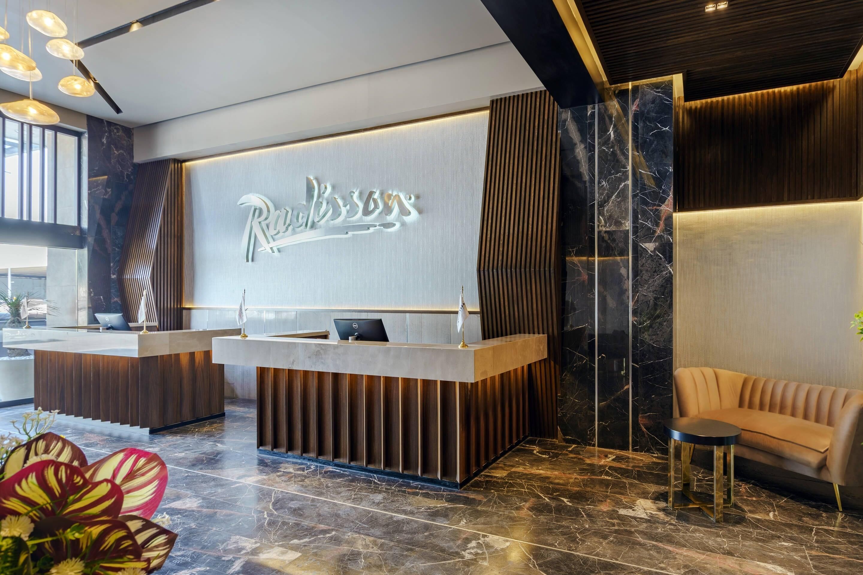 A reception desk with a modern design, a sofa, and a decorative plant.
