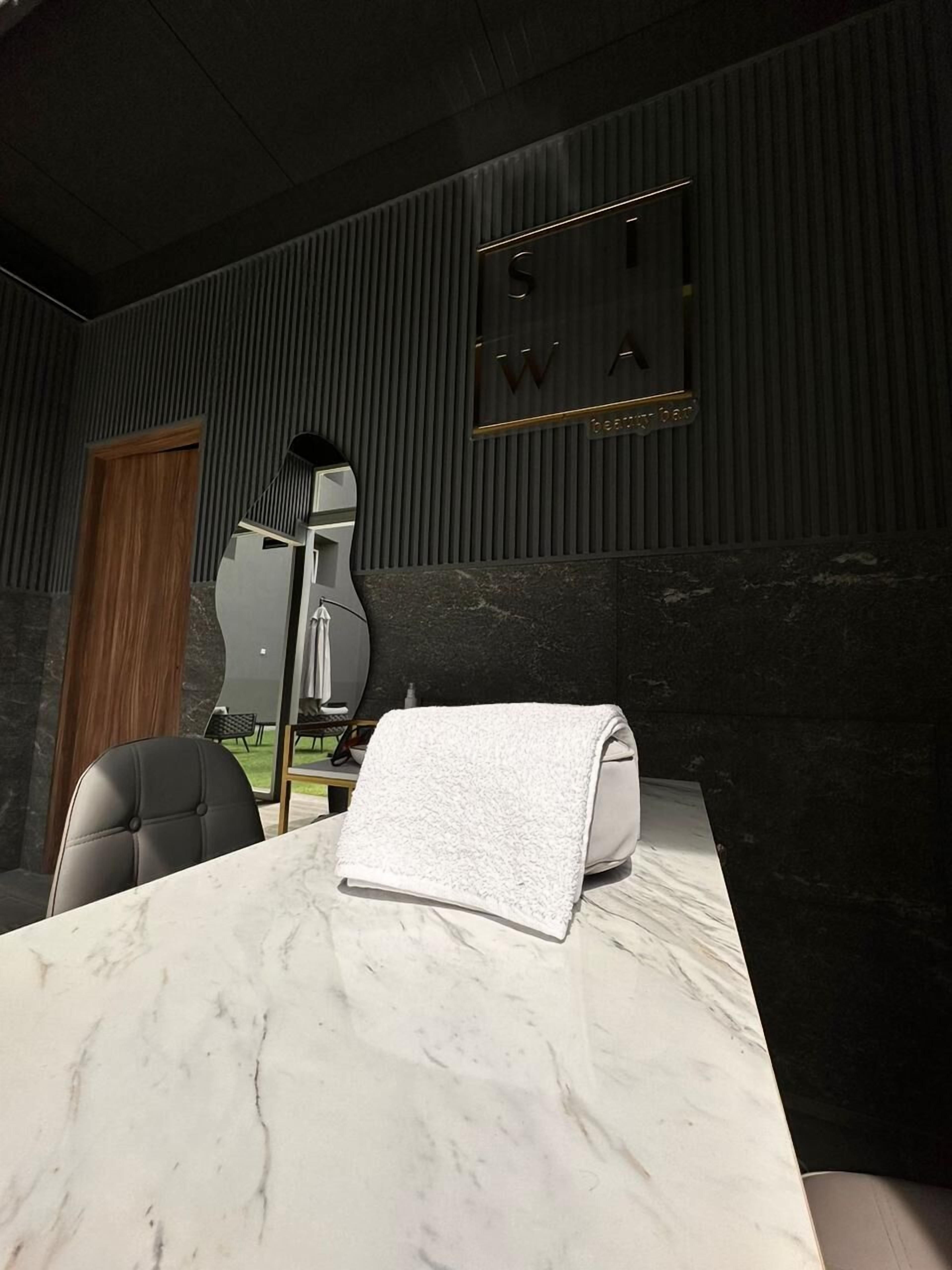 Een moderne badkamer met een marmeren aanrechtblad, een handdoek en een spiegel.