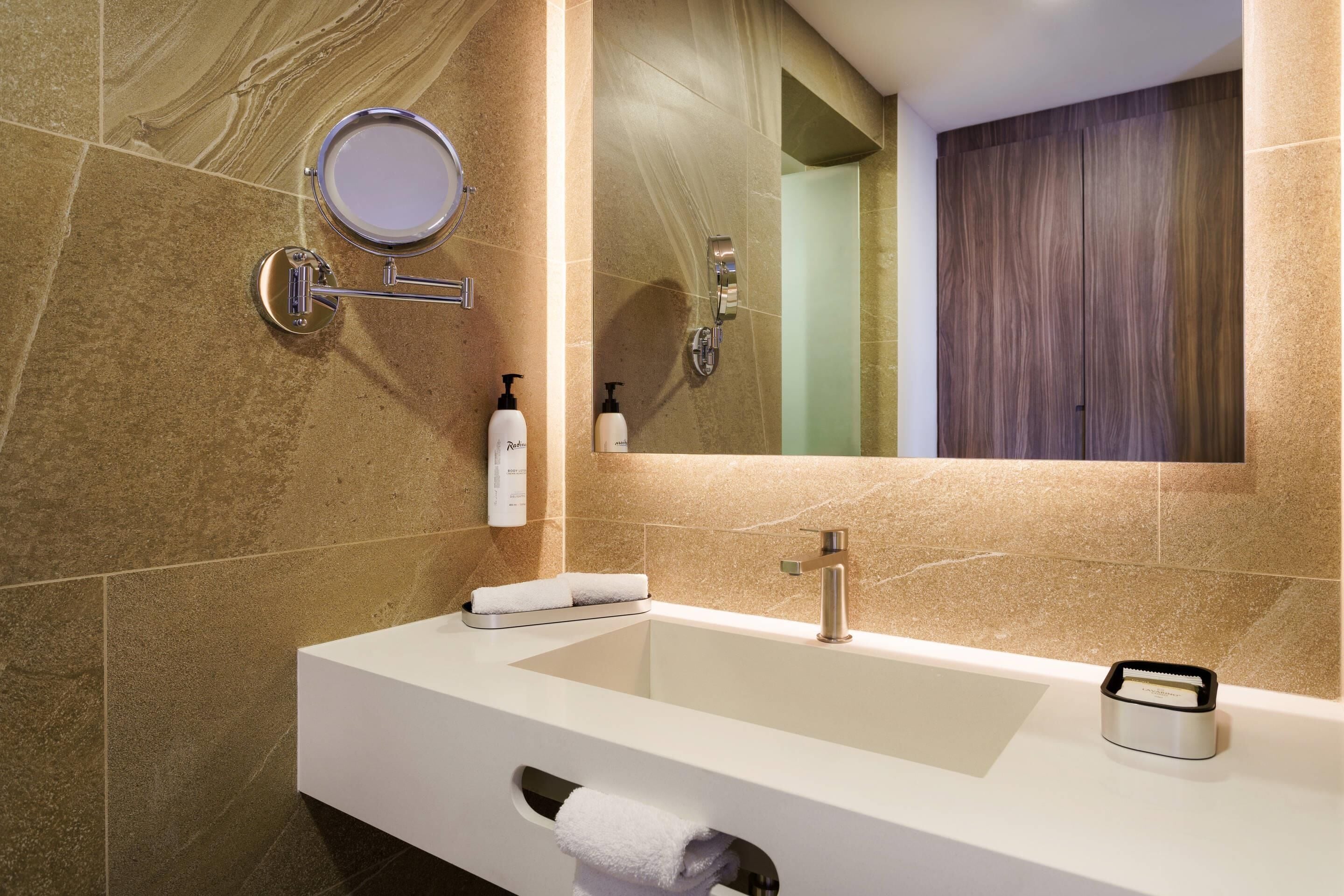 Un baño moderno con un lavamanos grande, un espejo y un perchero para toallas.