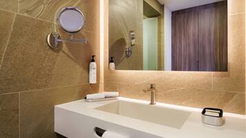 Un baño moderno con un lavamanos grande, un espejo y un perchero para toallas.