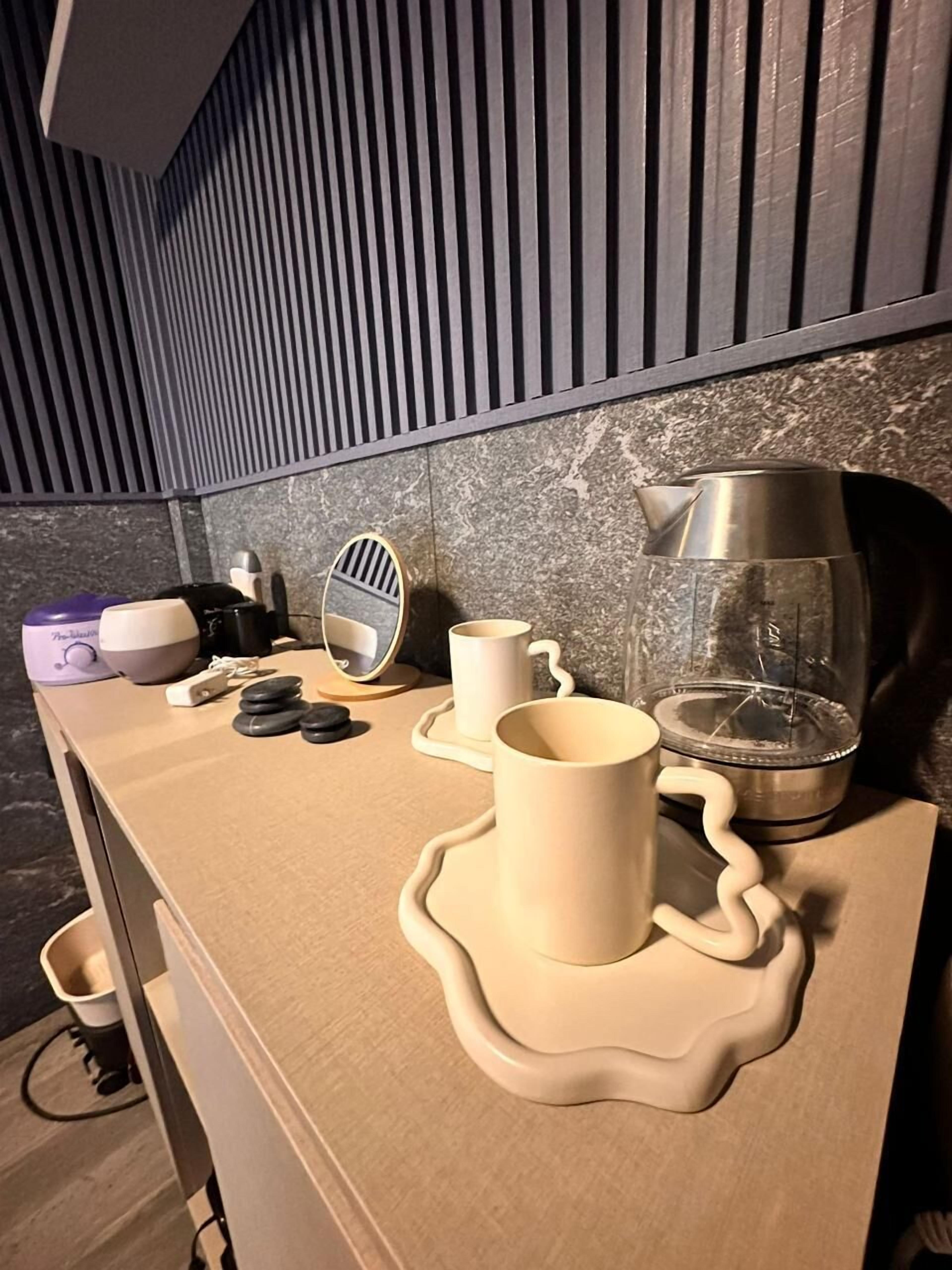 Eine Küchenarbeitsplatte mit Wasserkocher, Kaffeemaschine und einigen Tassen.