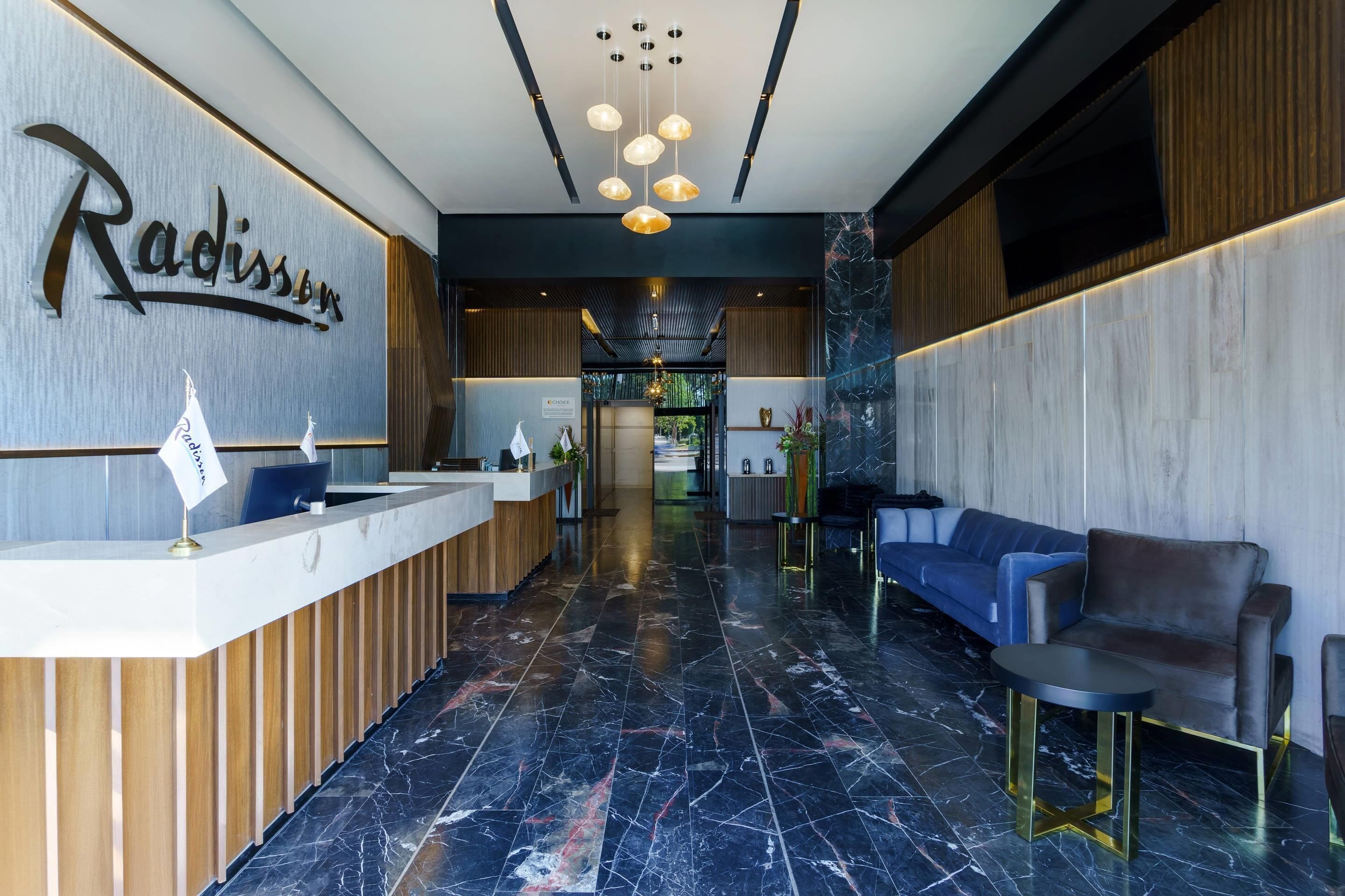 A reception area with a marble floor, a reception desk, a blue sofa, and a chandelier.