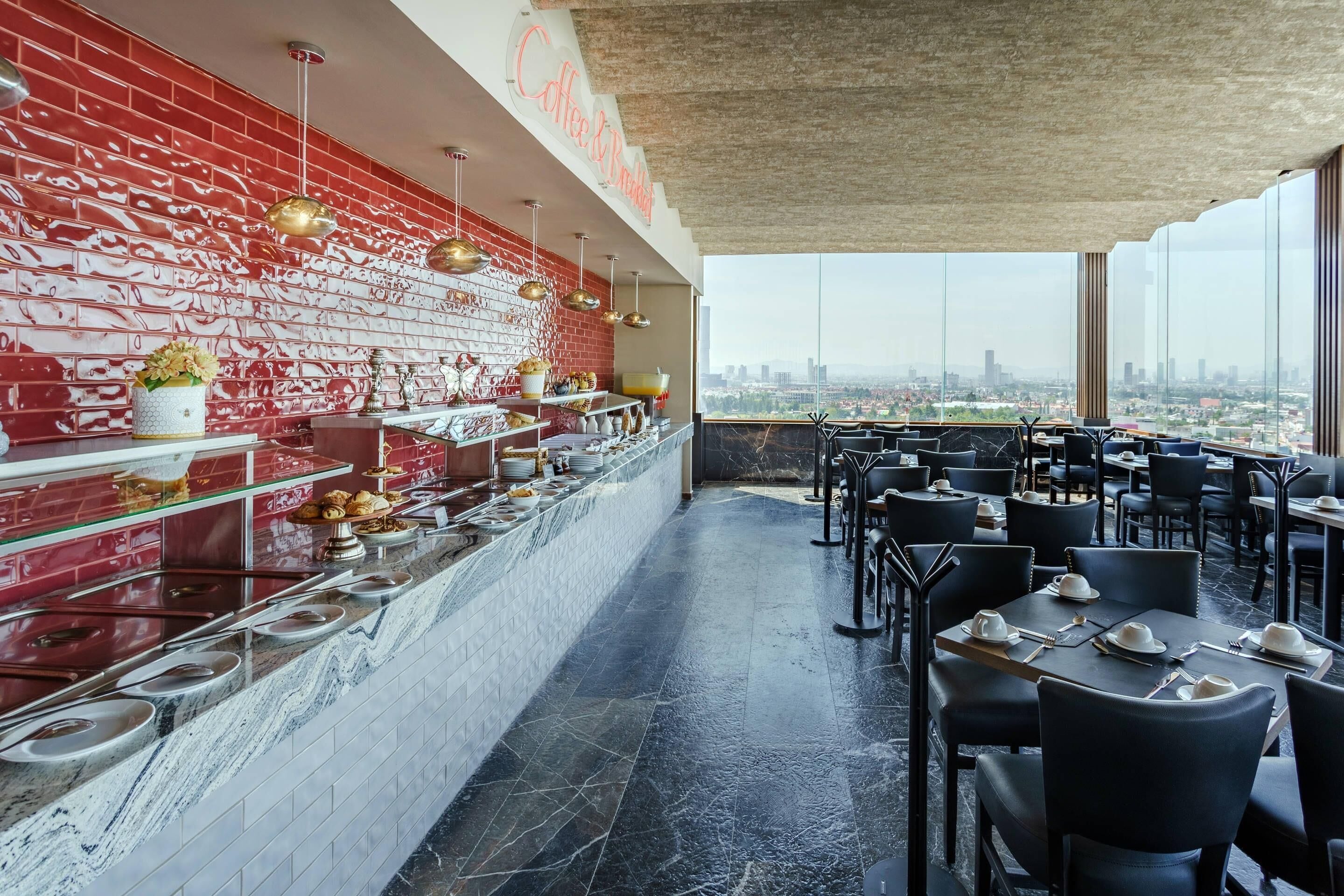 Un restaurante con pared de ladrillo rojo, mostrador de mármol y sillas negras.