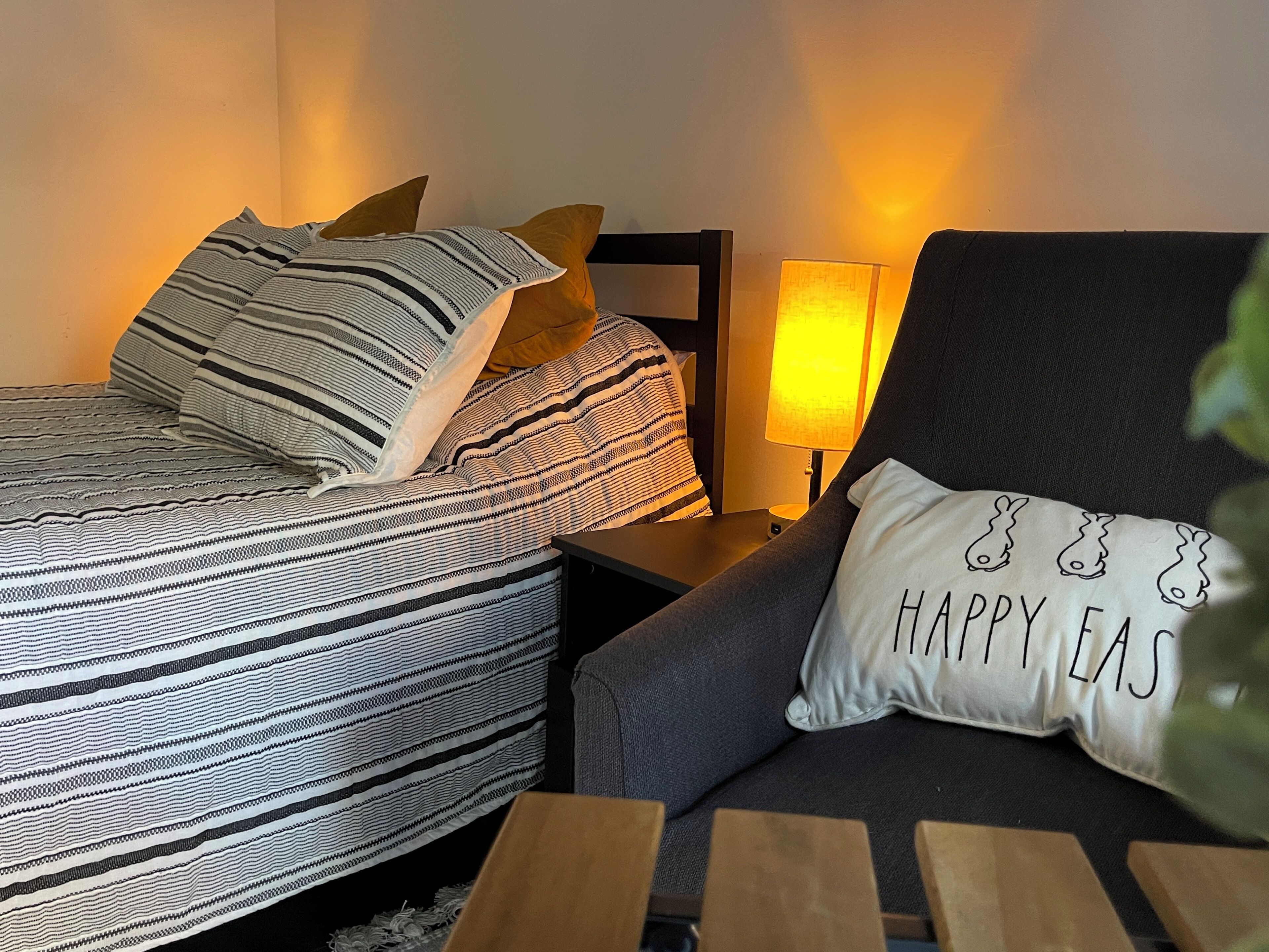 A neatly arranged bedroom with a bed, a chair, and a nightstand.